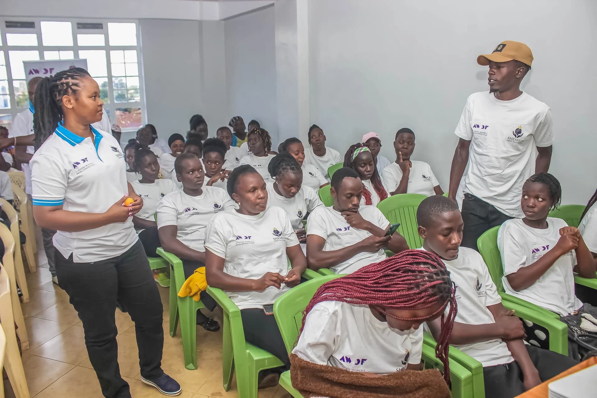 Two people stand among seated learners during a classroom discussion.