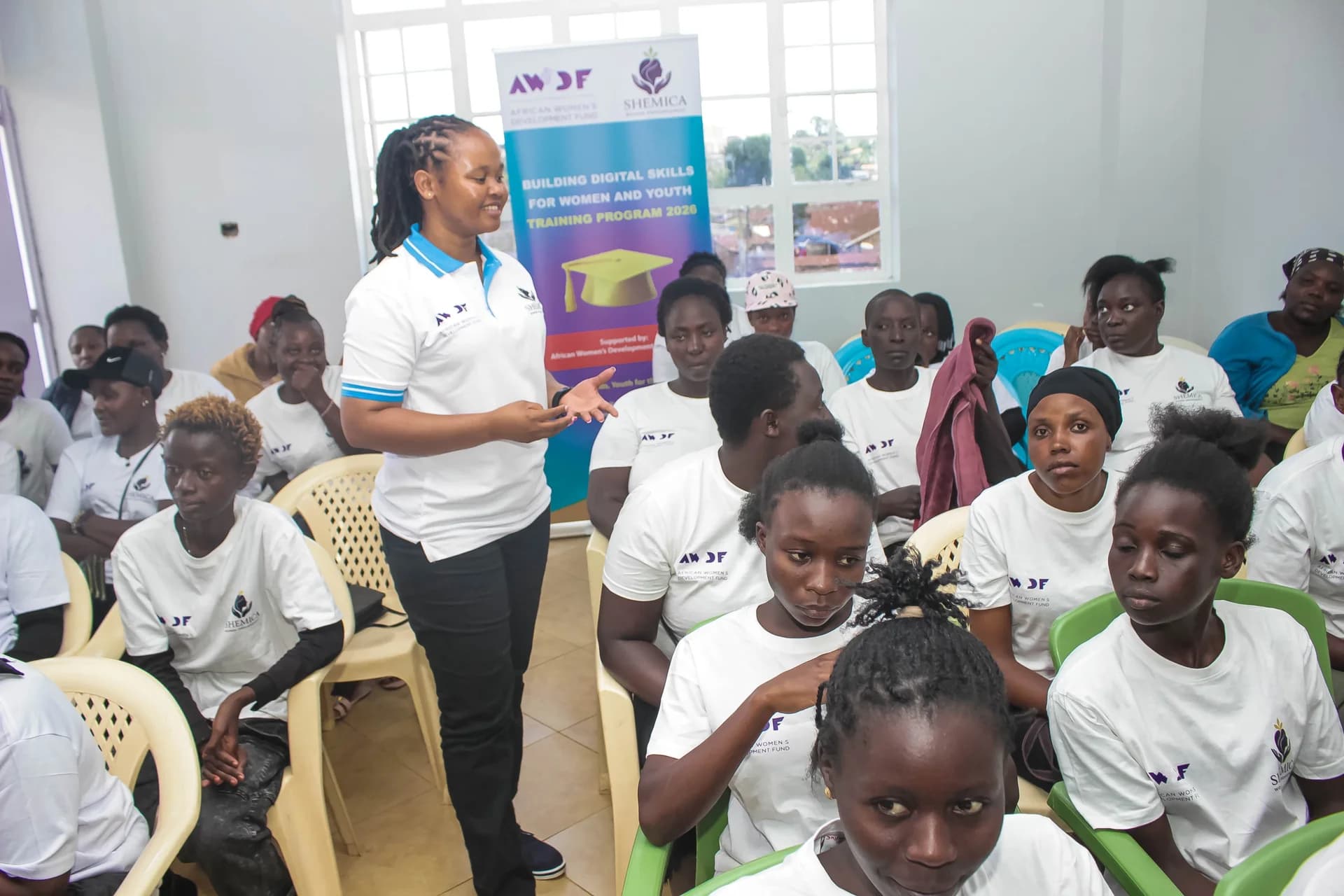 A facilitator leads a discussion with learners seated in a bright classroom.